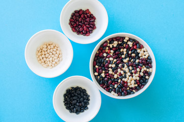 Tree types of dried beans in a white bowls on a light blue background. Top view. Healthy eating concept.