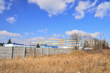 Budynki fabryki i nie bieskie niebo ponad betonowym ogrodzeniem.