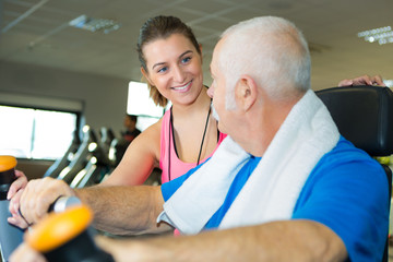 female coach helps a senior man doing exercises