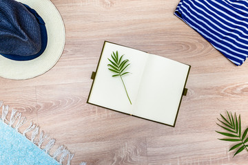 Top view of vacation accessories with blank notebook and summer beach items. Lay flat fashion background on wooden floor.