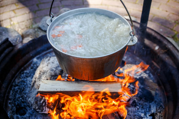A cauldron with fish soup, which is cooked on a fire