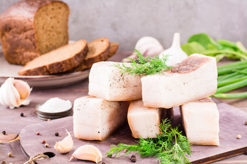 Salted lard with garlic and dill on a cutting board on a wooden table