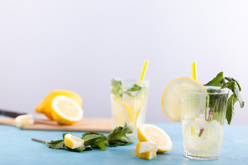 Homemade fresh detox water with lemons over gray background and sitting on blue vintage desk
