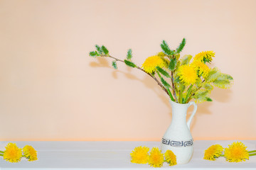 Bouquet of spring willow branches with dandelion flowers in a vase on a light background, copyspace,
