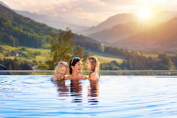 Family in swimming pool with mountain view - obrazy, fototapety, plakaty