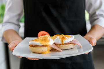 Obraz na płótnie Canvas Concept picture, chef is holding a egg benedict for breakfast