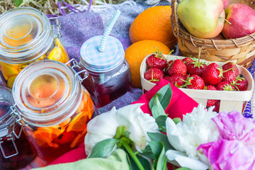 Picnic in the outdoor with strawberry, apples, pillows and cold beverages
