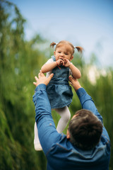 Fototapeta premium Dad and daughter dressed in jeans walking in the pakr and have fun