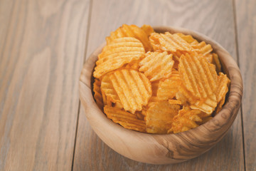 rippled potato chips in wood bowl with copy space