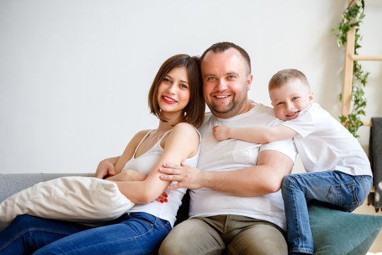 Picture of cuddling parents with son sitting on sofa