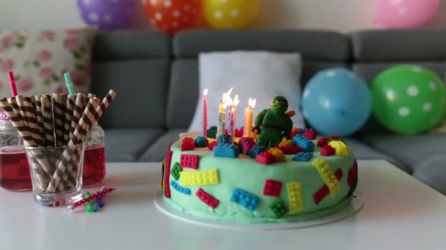 Cute child, preschool boy, celebrating his birthday with colorful cake, candles, balloons at home