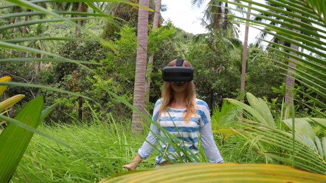 Virtual reality VR 3D headset and woman exploring the play on a background of nature jungle