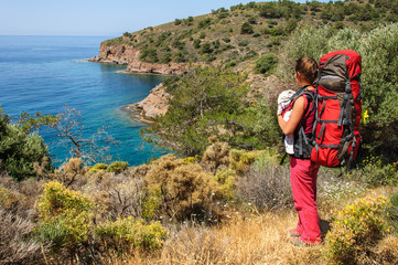 A woman with a baby in a sling and a large backpack travels along the Carian path. Turkey