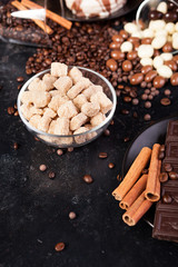 Chocolate tablets next to cinnamon rolls and other sweets and candies on a wooden background