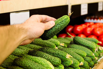 Man's hand selects fruits and vegetables from the supermarket shelves.