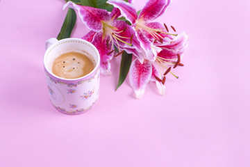 Pink background, cup of morning coffee and a bouquet of flowers of lilies. Free space for text