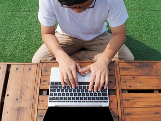 Top view of young Asian man using computer laptop at outdoors.