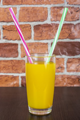 Orange juice Two straws Vitamins Health concept wooden background and brick wall