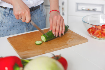 Young attractive woman cooking salad indoors at the kitchen