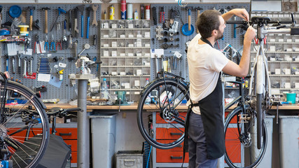 friendly and competent bicycle mechanic in a workshop repairs a bike