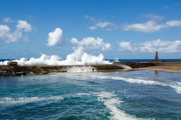 Big ocean waves breaking on the natural outdoor swimming pool in the small fishing village Bajamar. Tenerife, Canary Islands, Spain.