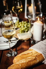 romantic dinner with a glass of wine, a baguette and snacks on an old wooden table on a summer evening