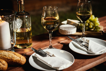 romantic dinner with a glass of wine, a baguette and snacks on an old wooden table on a summer...