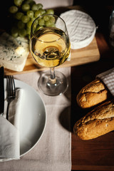 romantic dinner with a glass of wine, a baguette and snacks on an old wooden table on a summer evening