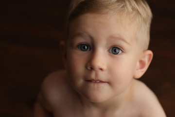 Close-up portrait of a small cute baby boy on a dark background