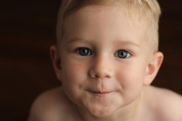 Close-up portrait of a small cute baby boy on a dark background