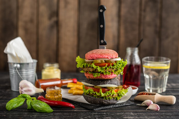 Tasty hamburger with meat and vegetables against a dark background. Fast food. It can be used as a background