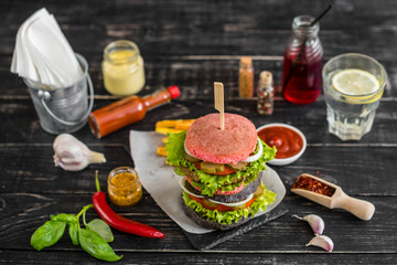 Tasty hamburger with meat and vegetables against a dark background. Fast food. It can be used as a background