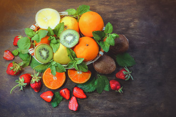 citrus fruits in a basket and strawberries on a wooden background