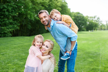 Fototapeta premium happy family with two kids smiling at camera while spending time together in park