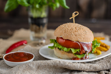 Tasty hamburger with meat and vegetables against a dark background. Fast food. It can be used as a background
