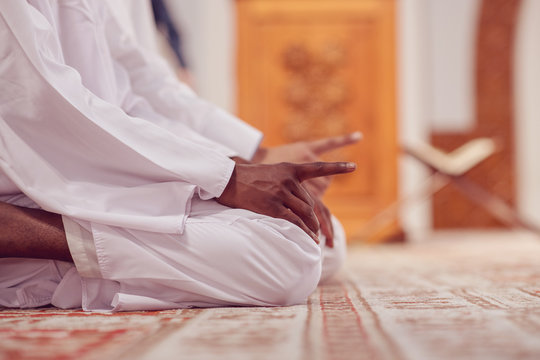 Two religious muslim man praying together inside the mosque.
