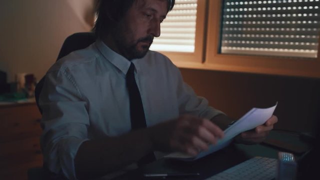Businessman reading document agreement disclaimer with magnifying glass in dark office interior