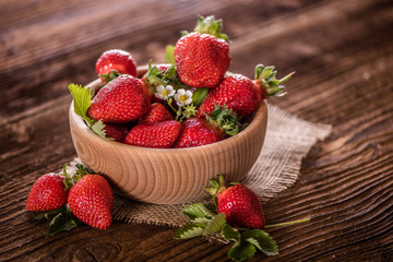 strawberries in wooden bowl on wood table