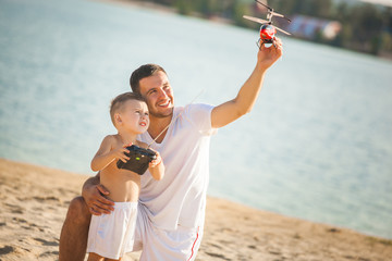 Young father playing helicopter with his little son outdoors