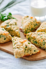 Savory scones with feta and mozarella and green herbs on a wooden board.