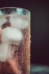 close-up of rose cocktail with ice cubes and condensed water on craquelured glass