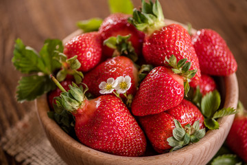 strawberries in wooden bowl on wood table