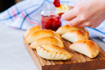 Homemade potato stuffed empanadas with ketchup on a wooden background. White stone background.