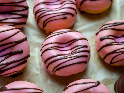 Close-up image of group of pink coating baked donuts with chocolate topping