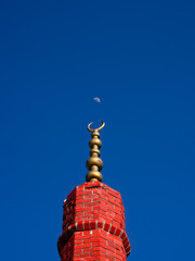 Turkish half-moon over the brick tower and real moon with blue sky background.