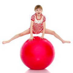 Fototapeta na wymiar A little girl is jumping on the big gym ball.