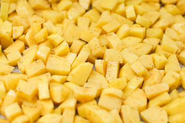 close up cut potatoes with seasoning on a tray in selective focus