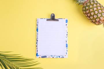 Tropical fruit, and a palm branch on a yellow background. Free space for text on a white board in the center. Copy space, flat lay.