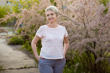 Fototapeta premium Portrait of a girl in a blooming garden. A woman is walking in the summer in the park. Happy middle-aged woman 