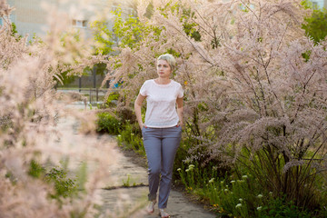 Portrait of a girl in a blooming garden. A woman is walking in the summer in the park. Happy middle-aged woman
